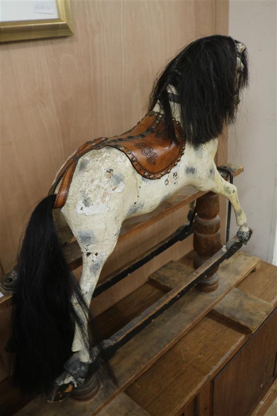 A Victorian painted carved wood rocking horse, with brass studded leather saddle, in trestle frame H.87cm